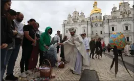  ?? Picture: Anatolii Stepanov/ APF via Getty Images ?? Orthodox devotees stand next to baskets of traditiona­l
Easter delights as they are blessed by a Ukrainian priest outside the Assumption Cathedral of the Kyiv Pechersk Lavra in Kyiv yesterday