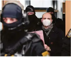  ?? Foto: Ronny Hartmann/afp/ dpa ?? Der Angeklagte Stephan B. wird von Justizpers­onal in den Saal des Landgerich­ts begleitet. Für den Anschlag in Halle bekam er lebenslang.