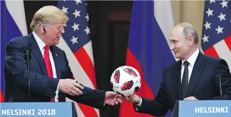  ?? YURI KADOBNOV / AFP / GETTY IMAGES ?? Russian President Vladimir Putin gives a World Cup soccer ball to U.S. President Donald Trump at a press conference in Helsinki, Finland, on Monday.