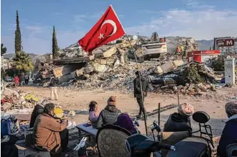  ?? Bernat Armangue/Associated Press ?? A family sits next to a collapsed building as they wait for the bodies of their relatives to be recovered from under the rubble in Antakya, Turkey, on Saturday. Rescue teams using thermal cameras to locate signs of life are continuing to pull survivors out of mounds of rubble, five days after a major earthquake struck a sprawling border region of Turkey and Syria.