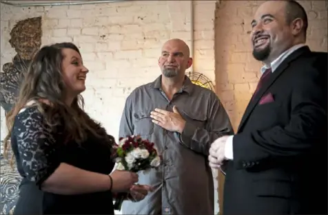  ?? Alexandra Wimley/Post-Gazette ?? Lt. Gov.-elect John Fetterman, center, officiates a wedding between Brittni Biddle, left, and Dominic Shuck, both of White Oak, in Mr. Fetterman’s home Dec. 21 in Braddock. The wedding was his last official act as mayor of Braddock.