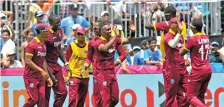  ?? – AFP ?? CLEVER BOWLING: Dwayne Bravo, centre, of West indies celebrates after leading his team to victory over India in the first of two T20s at Central Broward Stadium in Fort Lauderdale on Saturday.