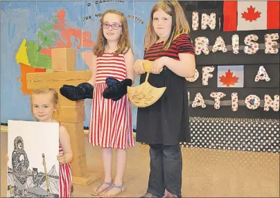  ?? ERIC MCCARTHY/JOURNAL PIONEER ?? Sophie Ford displays an Inuit art piece while her sister, Addison, models sealskin mittens and Alli Robinson shows an ulu tool used by the Inuit. The artifacts were part of a Nunavut display set up for Ellerslie Elementary School’s “In Praise of a...
