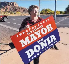  ?? RICK BOWMER/ASSOCIATED PRESS ?? Donia Jessop holds her mayoral campaign sign outside her store in Colorado City, Ariz., in October. Jessop’s election prompted mass resignatio­ns by members of a polygamous sect who live in the town.