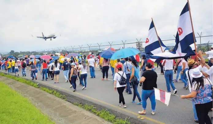  ?? SHIRLEY VÁSQUEZ ?? Los huelguista­s volvieron a hacer marchas por la vía frente al aeropuerto Santamaría, con lo cual provocaron atrasos a los viajeros que entraban o salían del país.