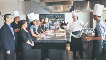  ??  ?? Chef Desmond (second right) demonstrat­es how to pull the dough for la mian. Chong is at far left while hotel manager Jayson at ninth left.