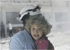  ??  ?? 0 A member of the White Helmets rescues a child after an airstrike