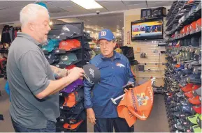  ?? JIM THOMPSON/JOURNAL ?? Fred Hultberg, right, gets help with a hat Friday from co-owner Andy Hageman at the House of Football in Albuquerqu­e