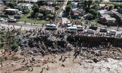  ?? Photograph: Marco Longari/AFP/Getty ?? Residents collecting clean water from a broken pipe sticking out from a collapsed embankment on the side of a road in Amaoti, north of Durban.