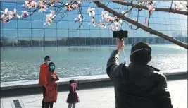  ?? ZENG JIA / FOR CHINA DAILY ?? A visitor takes selfies under a flowering magnolia tree at the National Grand Theater in Beijing on March 11.