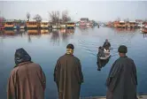  ?? New York Times ?? Villagers drink tea and discuss Kashmir’s political situation in Bandipora. ( Right) Boat owners at Dal Lake in Kashmir, a popular tourist destinatio­n in Srinagar.