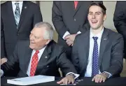  ?? Kevin Myrick / PSJ ?? Gov. Nathan Deal holds his hands over a line of pens next to Rep. Trey Kelley, R-Cedartown, after signing the 2018 budget.