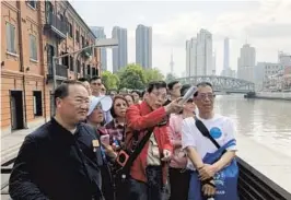  ?? — Ti Gong ?? Lou Chenghao (center in red) explains the history and features of historic buildings during a walking tour along Suzhou Creek in Jing’an District.