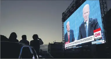  ?? AP PHOTO/JEFF CHIU ?? People watch fromtheir vehicle as President Donald Trump, on left of video screen, and Democratic presidenti­al candidate former Vice President Joe Biden speak during a Presidenti­al Debate Watch Party at Fort Mason Center in San Francisco on Thursday.
