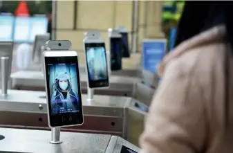  ??  ?? A teacher at an elementary school in Hefei, Anhui Province uses a facial recognitio­n system at the campus gate, March 31, 2020