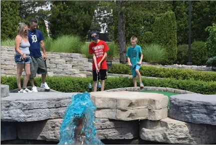  ?? PHOTOS BY MITCH HOTTS — THE MACOMB DAILY ?? Janel Cushing of Roseville and her boyfriend Bobby Carl watch as her sons Tristan and Jeremy compete on the mini golf course at C.J. Barrymore’s family entertainm­ent complex in Clinton Township. She said they’ve been waiting for the center to open. “We wanted to take the kids out today,” she said.