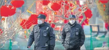  ?? AP ?? Security guards walk past decoration­s for a cancelled Lunar New Year temple fair at Longtan Park in Beijing on Saturday.