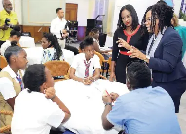  ??  ?? The Spectrum Management Authority Girls in ICT Day event on Thursday, April 26, 2018 saw fifth and fourth form Holy Trinity High School students and their IT teacher Otis Mitchell (seated at right) chatting with Steffyann Brown-Bisnauth (standing,...