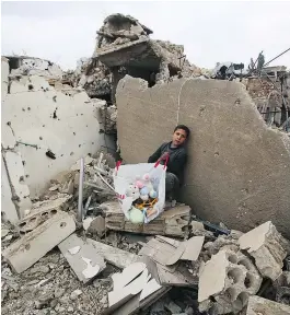  ?? — GETTY IMAGES ?? A Syrian boy sits clutching his belongings in the rubble of his house in Aleppo’s Al-Arkoub neighbourh­ood.