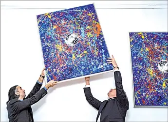  ??  ?? Kerem (left) and German art dealer Marcus Schaefer (right) hang a print edition of Mikail and Neuer’s painting ‘Manus 11’ prior to the opening of ‘Manus 11’ exhibition in Berlin. — AFP photos