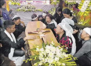  ?? Hau Dinh The Associated Press ?? Relatives of Bui Thi Nhung weep as they gather around Nhung ’s casket at the family home Saturday in Do Thanh, Vietnam. The 19-year old was among the 39 Vietnamese who died while being smuggled in a truck to England.