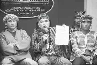  ?? (PNA) ?? FOR THE SAFETY OF IPs. Chairman of the Mindanao Indigenous Peoples (IP) Council of Elders and Leaders, Datu Joel Unad (center), presents to the press a resolution signed by the council, condemning the violations on IP rights perpetrate­d by the Communist movement, during a press briefing held at Camp Aguinaldo in Quezon City on Thursday (Dec. 6, 2018). The council said it came up with Resolution 20 (series of 2018) to “preserve the peace and protect the Ancestral Domain for the safety and general welfare of the Mindanao ICCs/IPs.”
