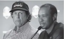  ?? AP PHOTO/MATT SLOCUM ?? Phil Mickelson, left, listens to Tiger Woods speak during a 2018 news conference where they were announced as captain’s picks for the 2018 U.S. Ryder Cup Team in West Conshohock­en, Pa. They have combined for 124 wins on the PGA Tour, and Mickelson believes they’re not done.