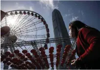  ?? In the central district of Hong ?? A woman walks past an observatio­n wheel Kong on Thursday. — afp