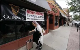  ?? ASSOCIATED PRESS FILE PHOTO ?? A traveller wheels her baggage past a now hiring sign outside a bar and restaurant in Sioux Falls, S.D.