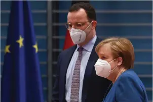  ?? The Associated Press ?? ■ German Chancellor Angela Merkel and Federal Health Minister Jens Spahn arrive at the weekly cabinet meeting wearing face masks Wednesday in Berlin, Germany. The coronaviru­s pandemic is colliding with politics as Germany embarks on its vaccinatio­n drive and one of the most unpredicta­ble election years in its post-World War II history.