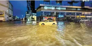  ?? —afp ?? Absolute carnage: a taxi driving through a flooded street following heavy rains in dubai.