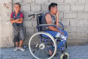  ??  ?? A file photo of Jetullah Veliu, 16, sitting on a wheelchair along a street in the Roma neighbourh­ood in the town of Mitrovica —