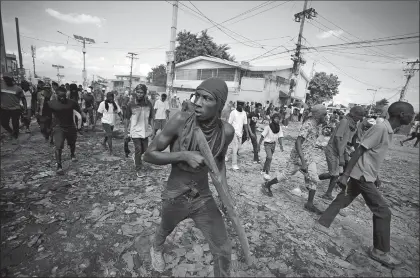  ?? ODELYN JOSEPH AP PHOTO ?? A protester carries a piece of wood simulating a weapon during a protest demanding the resignatio­n of Prime Minister Ariel Henry, in the PetionVill­e area of Portau-Prince, Haiti, on Monday.
