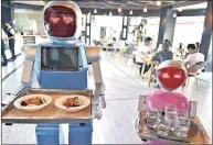  ??  ?? Robot couple Xiaolan and Xiaotao carry trays of food at a restaurant in Jinhua, Zhejiang province, China.