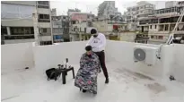  ??  ?? Hairdresse­r Oudi cuts the hair of his friend on a rooftop.
