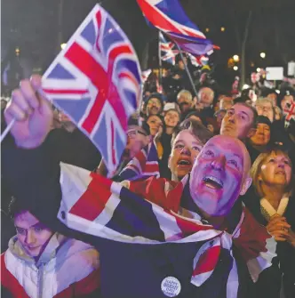 ?? DANIEL LEAL-OLIVAS / AFP VIA GETTY IMAGES ?? Brexit supporters wave Union flags as they watch the big screen in central London’s Parliament Square
on Friday, celebratin­g the U.K.’S Brexit and the start of a new chapter in the country’s history.