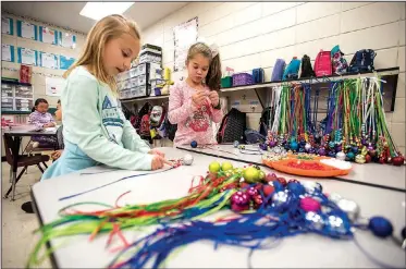  ?? NWA Democrat-Gazette/SPENCER TIREY ?? Kindergart­en students Analie Dryer (left) and Kendall Langley work Friday on making jingle bell necklaces in Cristine Eubanks’ class at Thomas Jefferson Elementary School in Bentonvill­e. This is the third year the class has done the project to raise...
