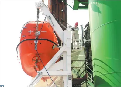  ?? XINHUA ?? A man checks a wind power generating facility installed on a ship of an offshore engineerin­g company in Qidong, Jiangsu province. The city has innovated shipping-related technology in recent years to improve efficiency.