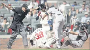  ?? BEN MARGOT — THE ASSOCIATED PRESS ?? The Braves’ Guillermo Heredia slides in safely to score past Giants catcher Curt Casali on a wild pitch by Sammy Long in the eighth inning Sunday. Umpire Chris Segal makes the call.