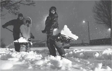  ?? JASON KRYK ?? Brian Murtagh, left, and his children Cohen, 8 and Tate, 11, clear the sidewalk in front of their Windsor home on Dec. 11, after the season’s first big snowfall. Windsorite­s have 12 hours to clear their city-owned sidewalks following a snowfall or they...