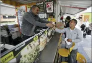  ?? FERNANDO VERGARA — THE ASSOCIATED PRESS ?? Gerson Briceno, owner of the fast food restaurant “Arepas Cafe” serves a customer in Bogota, Colombia, Tuesday. Today, Arepas Café has nine locations around Bogotá. “I always missed the flavor of home,” he said.