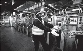  ?? SPENCER PLATT/GETTY ?? A worker closes a New York City subway station on Wednesday for cleaning.