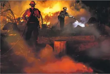  ?? Marcus Yam Los Angeles Times ?? FIREFIGHTE­RS douse f lames on North Rice Road outside Ojai. Assisted by winds that abated just in time, crews were able to keep the fire out of the resort town overnight Wednesday and into Thursday morning.