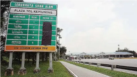  ??  ?? Lowered rates: A toll highway signboard with the old toll charges blacked out at the Kemuning toll plaza on Kesas Highway.