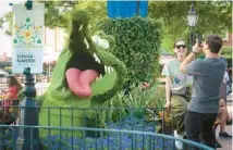  ?? JOE BURBANK/ORLANDO SENTINEL ?? Guests snap photos of a topiary of the Tick-Tock Croc, from the film “Peter Pan,” on Feb. 28, the opening day of the EPCOT Internatio­nal Flower & Garden Festival at Walt Disney World. The festival’s launch — and Leap Day — helped boost tourist-tax revenues in February.