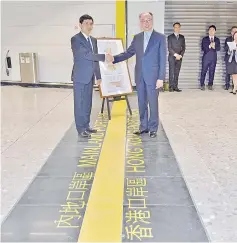  ?? — AFP photo ?? Photo shows Hong Kong Transport and Housing Secretary Frank Chan Fan (right) handing over the plans of the Mainland Port Area to the Yang Xiuyou, deputy secretary-general of the Shenzhen Municipal People’s Government, at a ceremony to mark the commission­ing of the Mainland Port Area at the new West Kowloon terminus in Hong Kong.