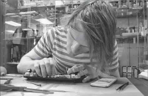  ?? TONY DAVIS/ THE GUARDIAN ?? Ben Bain fixes the display on a Wii U game controller at his shop, Geno Games, in Charlottet­own.