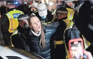  ?? ALBERTO PEZZALI THE ASSOCIATED PRESS ?? A woman is detained by police during “The Million Mask March” in central London on Thursday. The march was taking place on the same day national lockdown rules come into force in Britain.