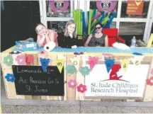  ?? CONTRIBUTE­D PHOTO ?? Kelsi Goins, left, and her friend Elie Mae Fletcher, center, wait for customers at their lemonade stand in Harriman, Tenn., earlier this month. Kelsi’s mother, Melissa Goins, right, supervises the operation.