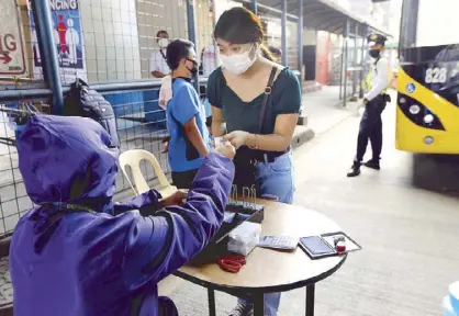  ?? BOY SANTOS ?? A Department of Transporta­tion employee collects fare from a passenger about to board a pointto-point bus at the North EDSA Terminal in Quezon City yesterday.